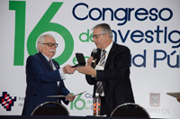 El doctor Jaime Martuscelli, coordinador de asesores de la Rectoría de la UNAM, recibe del doctor Mauricio Hernández, director general del Instituto Nacional de Salud Pública, el reconocimiento que el INSP hizo al doctor José Narro Robles, rector de la máxima casa de estudios, con la Conferencia 'Miguel E. Bustamante'.